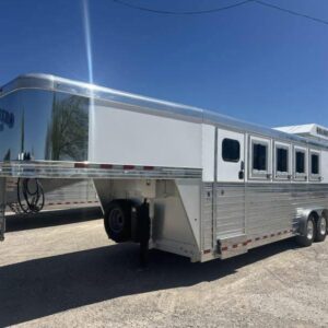 A sleek, all-aluminum 2020 Bloomer 4 Horse Stock Combo Trailer with a gooseneck hitch. The trailer has a stock-style design with open slats and a solid roof.