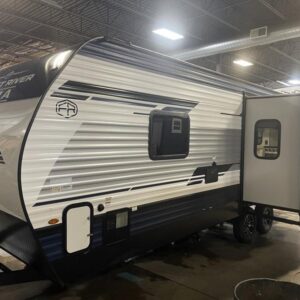 A 2025 Palomino Puma 227RK travel trailer, a new model with a white exterior and graphics. The RV features a single slide-out and an 18-foot power awning with LED lights. The image shows the RV parked in an outdoor setting.
