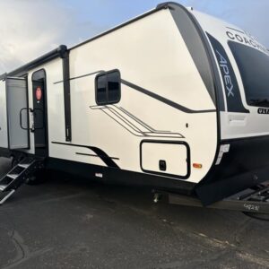 A 2025 Coachmen Apex 293 RLDS travel trailer, with a white exterior and graphics. The RV has a sloped front cap and two slide-outs, along with a large power awning. It is shown parked in an outdoor setting.