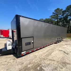 A charcoal gray 8.5x36TTA race trailer, shown in a clean, outdoor setting to highlight its large size and professional finish.