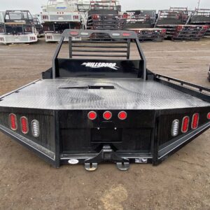 A Hillsboro G2 Steel Truck Bed, a heavy-duty flatbed for a pickup truck. The bed is black with a diamond-plate steel deck, and features a gooseneck hitch, receiver hitch, and a protective headache rack.